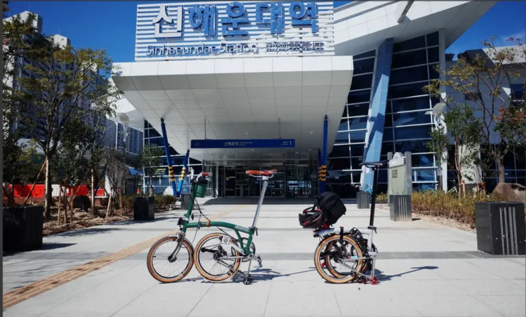 청명한 하늘 아래 신해운대역 앞에 나란히 놓인 TACO의 CHPT3 V4와 아내의 M4L 레이싱그린 브롬톤 자전거