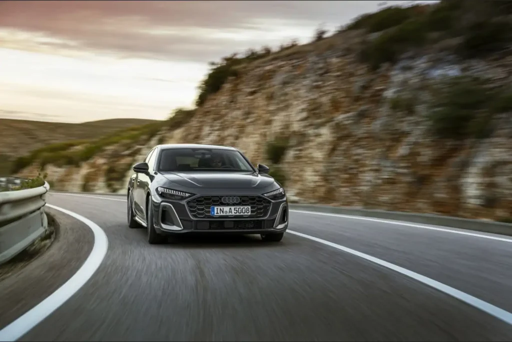 산악 도로에서 주행 중인 검은색 Audi RS5 스포트백 모습. 구불구불한 와인딩 로드를 달리는 장면으로 모션 블러 효과가 적용된 동적인 주행 사진. M340i의 경쟁 모델인 아우디 스포츠카