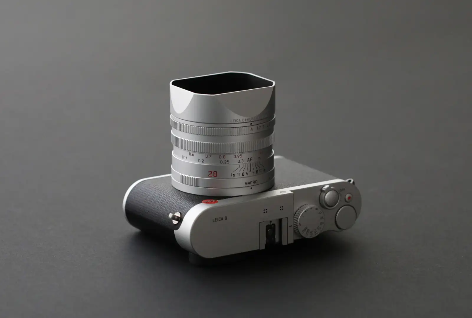 실버 크롬 바디의 라이카 Q 탑 뷰. 사각형 렌즈 후드가 장착된 Summilux 28mm f/1.7 렌즈 배럴에 최소 초점거리 0.17m, MACRO 각인, 조리개 눈금이 선명하게 새겨져 있다.