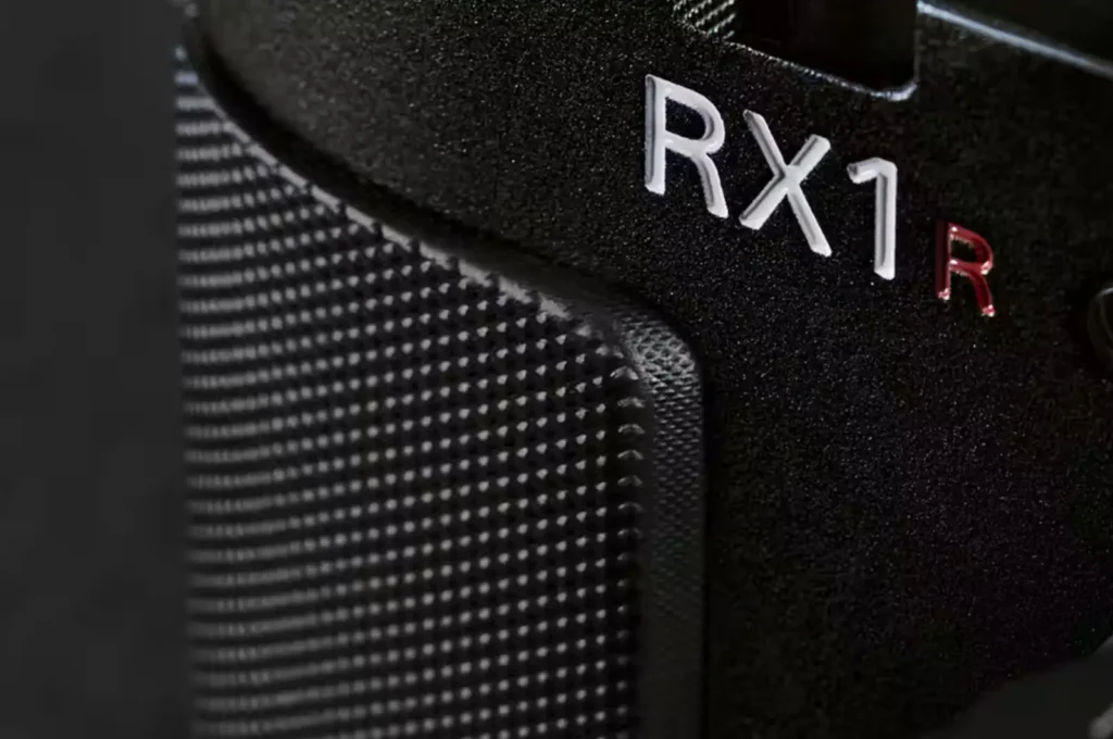 소니 RX1 시리즈 로고 클로즈업, 정교한 그립 텍스처와 빨간 R 마킹이 돋보이는 프리미엄 디자인 디테일