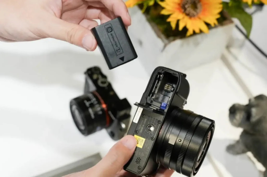 소니 RX1R III 카메라에 NP-FW50 배터리를 교체하는 모습, 기존 NP-BX1 대비 향상된 배터리 용량과 사용성을 보여주는 실제 사용 장면