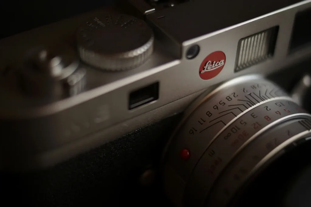 Leica M 시리즈 클로즈업 사진. 빨간 Leica 로고, 셔터 다이얼, 수동 초점 거리계가 강조된 모습.