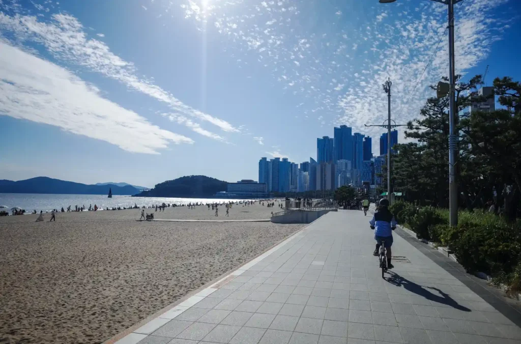 해운대 해수욕장에서 브롬톤으로 해변 라이딩을 즐기는 모습, 고층빌딩과 바다가 어우러진 풍경