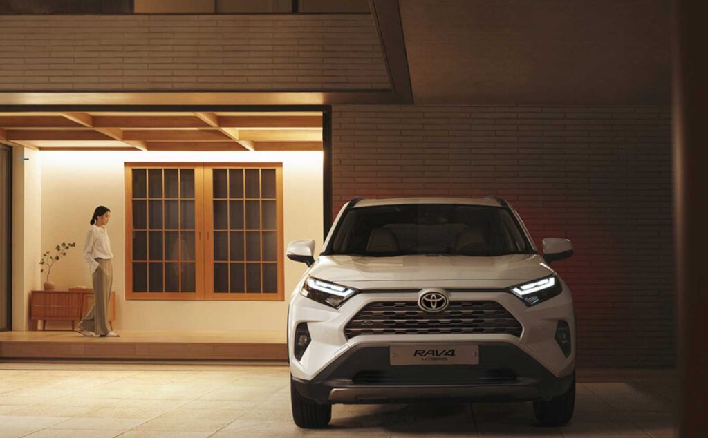 현대적인 주택 차고에 주차된 토요타 RAV4 하이브리드와 집 안에서 편안하게 지내는 여성의 일상적인 모습