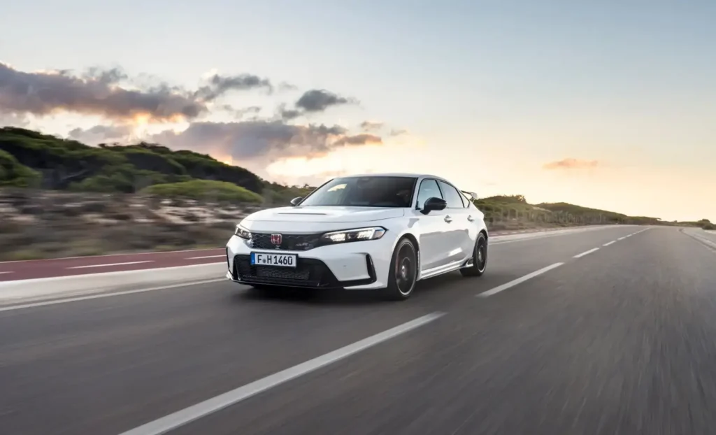 석양 배경의 도로에서 역동적으로 주행 중인 화이트 컬러의 혼다 시빅 11세대 모습