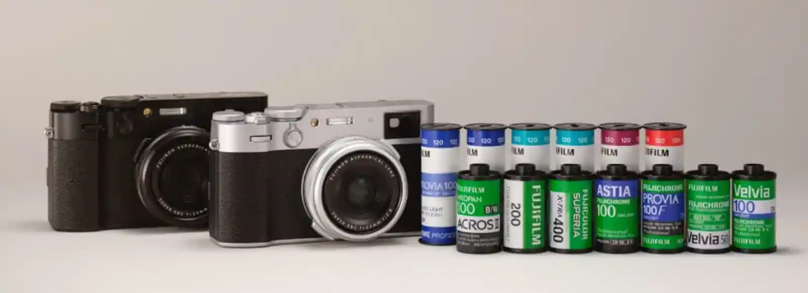 후지필름 필름 롤과 카메라. 후지필름 카메라 두 대 옆에 벨비아, 프로비아 등 다양한 종류의 필름이 놓여 있다.