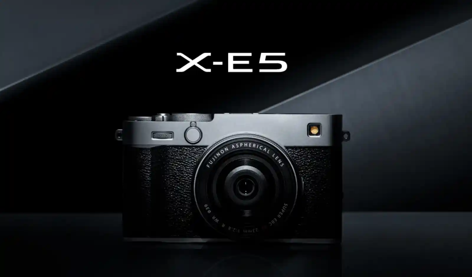 후지필름 X-E5 카메라 정면 사진, X-E5 로고와 함께 검은색 배경에 놓인 은색 바디와 XF 23mm F2.8 렌즈가 보인다.