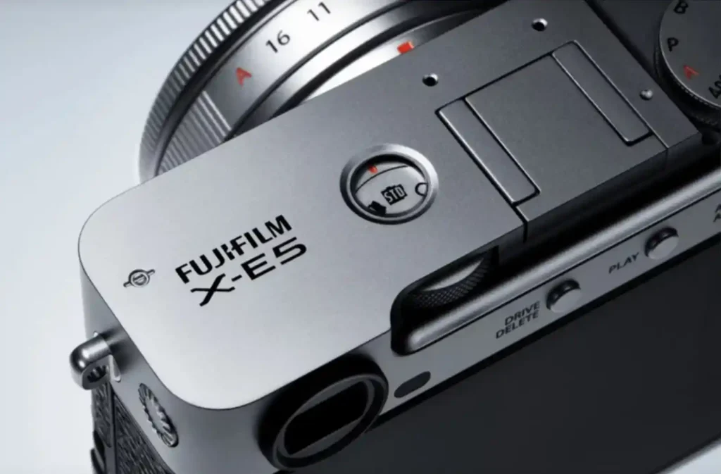 후지필름 X-E5 카메라 상단부 클로즈업 사진, 'FUJIFILM X-E5' 로고와 함께 필름 시뮬레이션 다이얼이 선명하게 보인다.