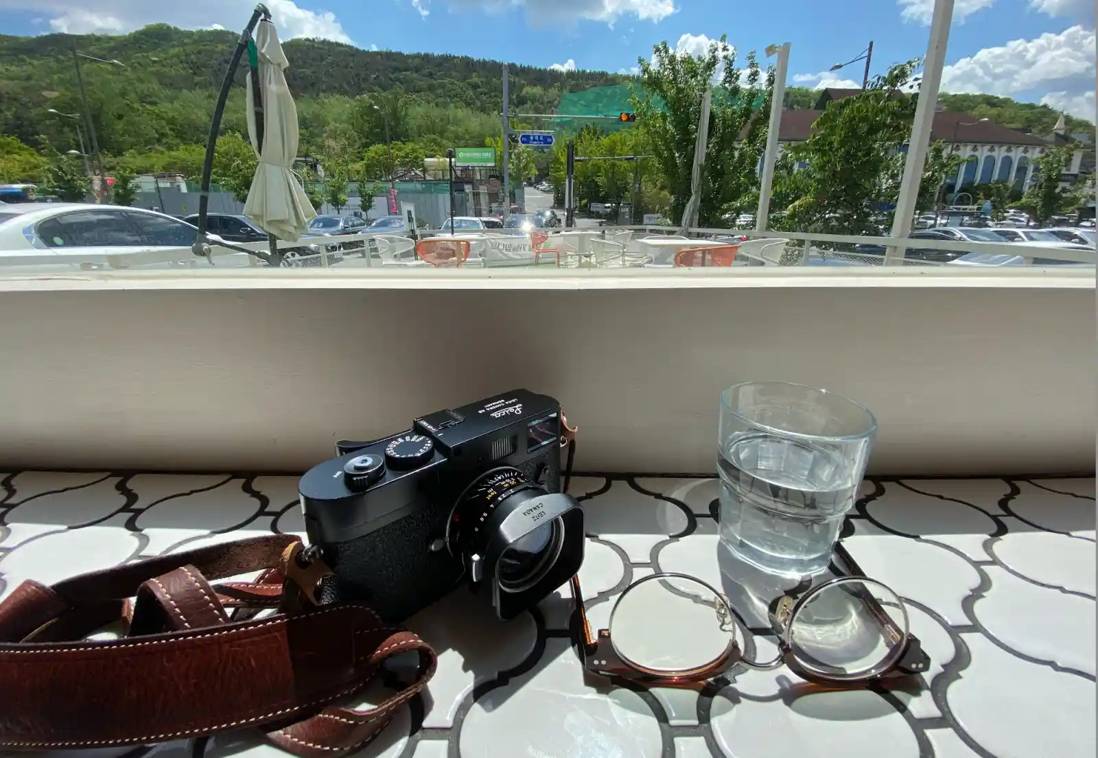 카페 창가 테이블 위에 놓인 라이카 M9-P 카메라와 안경