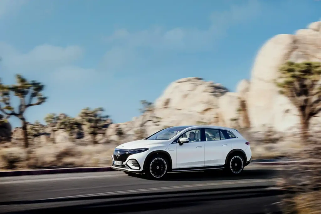 바위 지형의 도로를 달리고 있는 흰색 벤츠 EQS SUV. 역동적인 주행 사진으로 럭셔리 SUV의 매력을 보여줍니다.