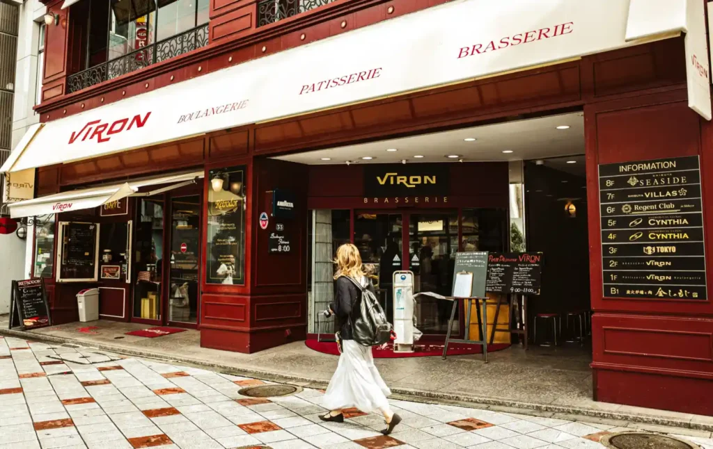 도쿄 시부야의 브랏스리 비론(VIRON) 건물 외관. 프랑스풍의 붉은색 건물 앞에 하얀색 치마를 입은 여성이 지나가고 있다.