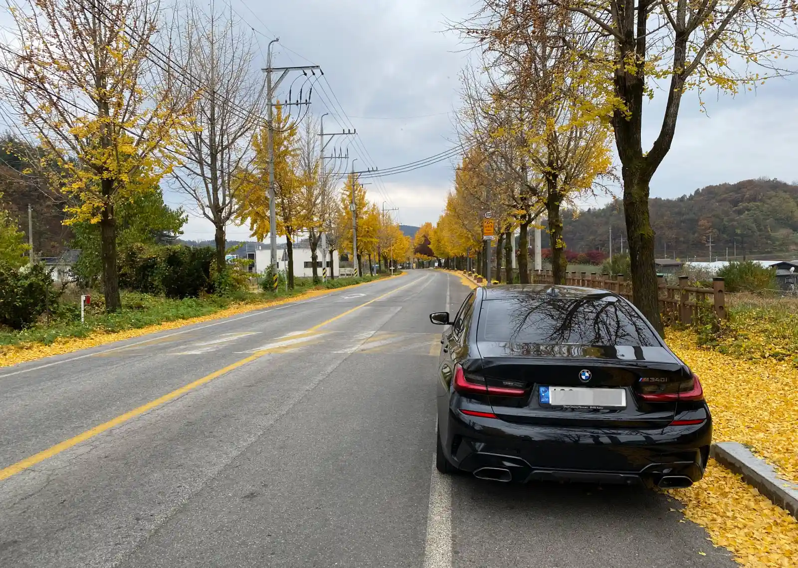 가을 단풍이 물든 도로에 주차된 검은색 BMW M340i 후면. 수입차 리스 할부 현금 구매 비교 포스팅. BMW 오너의 이야기.
