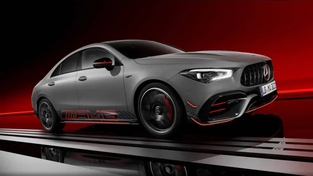 회색 메르세데스-벤츠 CLA 45 S AMG 차량이 붉은색과 검은색 배경의 스튜디오에서 측면을 보여주며 역동적으로 서 있다. 차체 측면에는 'AMG' 데칼이 붙어 있고, 휠 안쪽의 붉은색 브레이크 캘리퍼가 보인다.