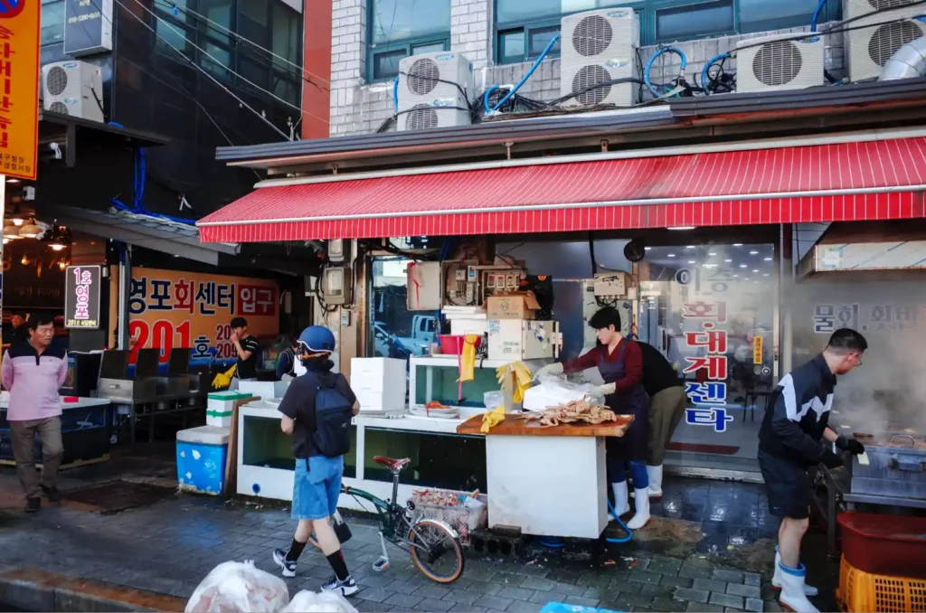 죽도시장 해산물 가게에서 상인과 손님들이 활기차게 거래하는 모습과 끌바중인 브롬톤