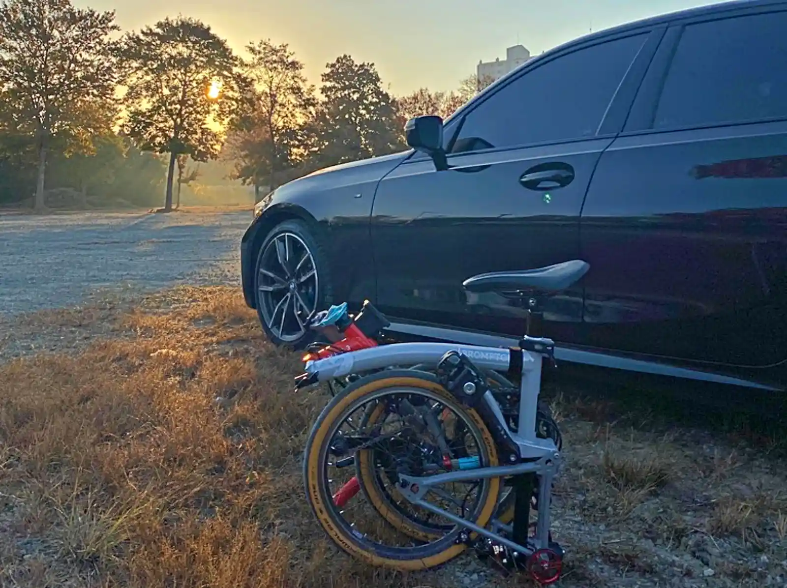 폴딩자전거 브랜드 브롬톤과 BMW M340i가 석양 배경 여행지에 함께 있는 모습