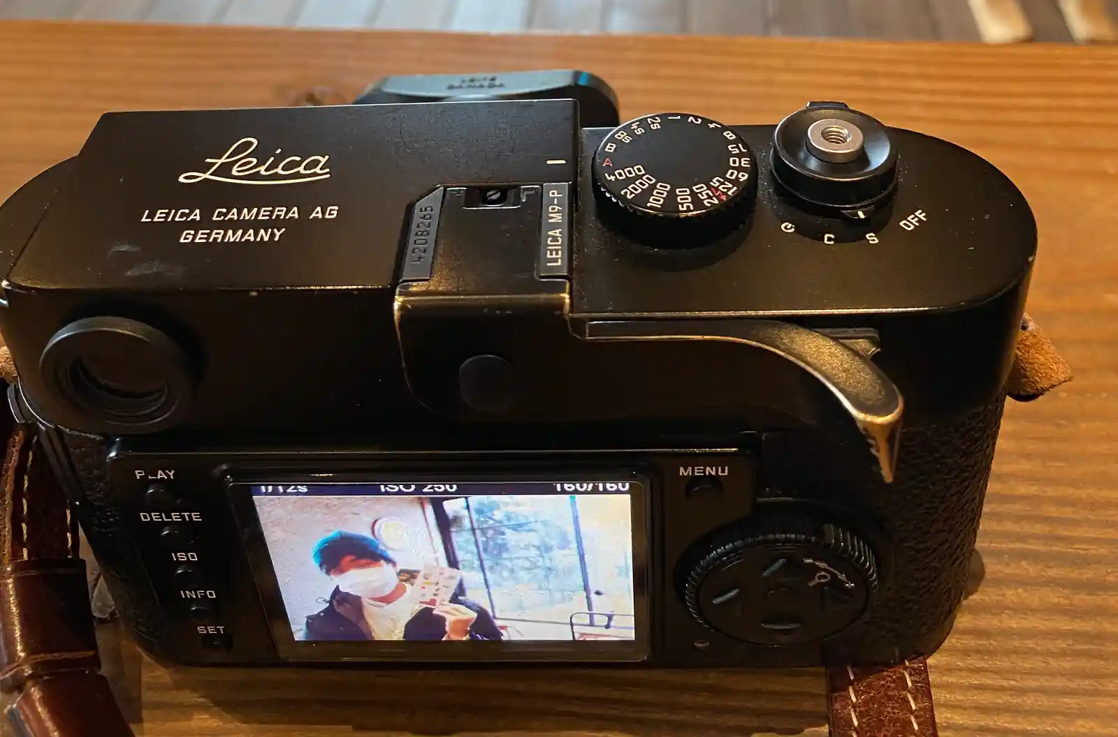라이카 M9-P 카메라 후면 모습, LCD 화면에 촬영된 이미지가 표시되어 있고 나무 테이블 위에 놓여진 모습