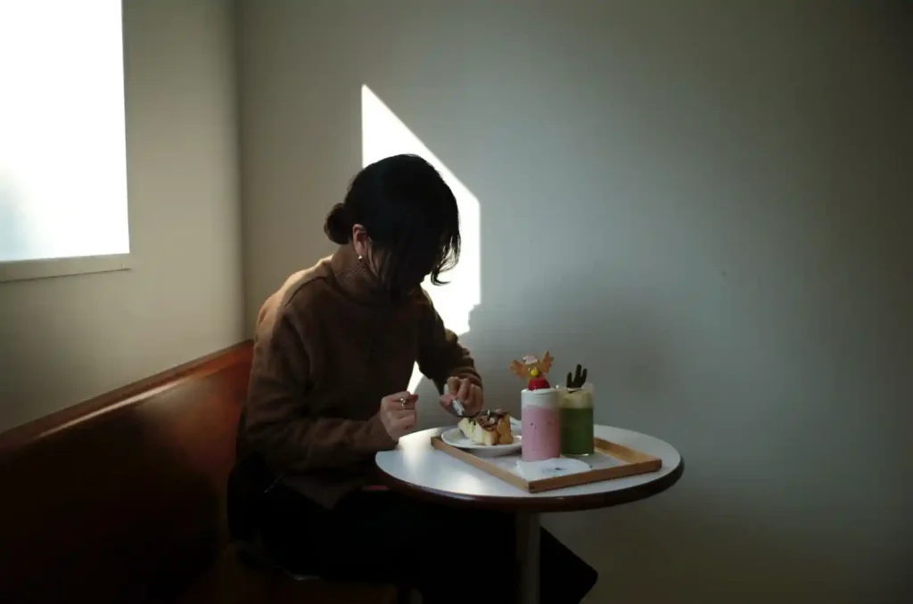 카페에서 디저트를 먹는 여성, 자연광이 들어오는 조용한 공간, 레인지파인더로 포착한 일상