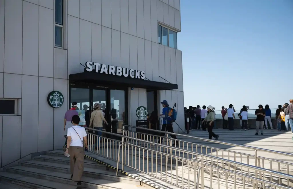 애기봉평화생태공원 전망대 1층 스타벅스 입구와 테라스에서 북녘 방향을 바라보는 방문객들. 맑은 하늘 아래 남북 접경의 고요한 풍경이 펼쳐져 있다.