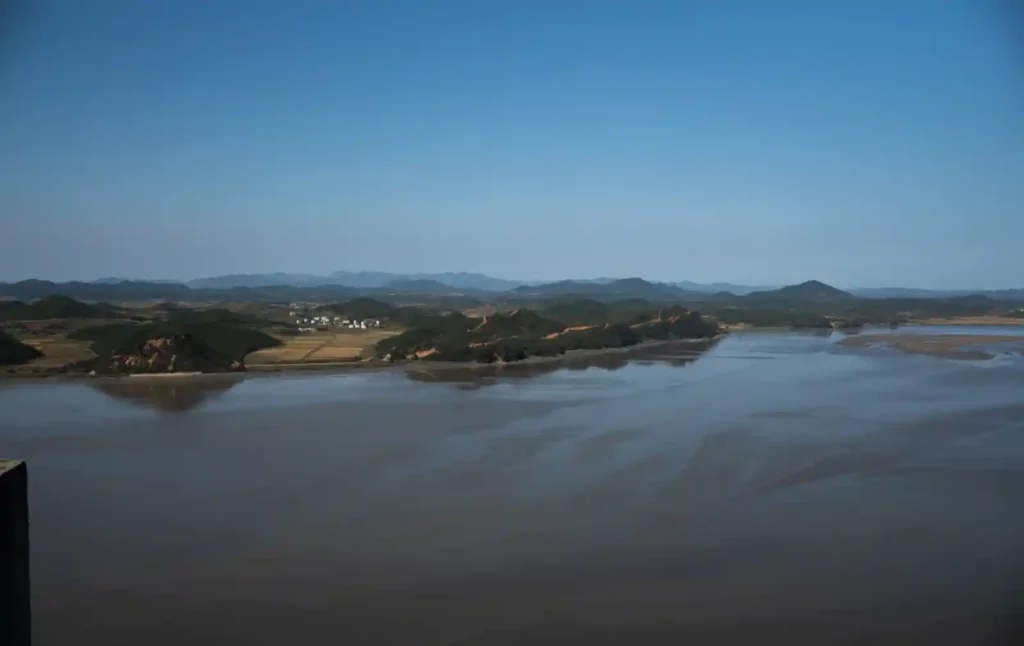 애기봉평화생태공원 전망대에서 바라본 북한 개풍군의 들판과 마을 전경. 강 건너편으로 논밭과 하얀 지붕의 집들이 평화롭게 자리하고 있다.