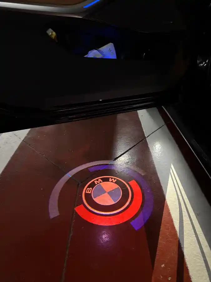 BMW M340i door light projecting BMW logo on the ground — night interior lighting detail by TACO