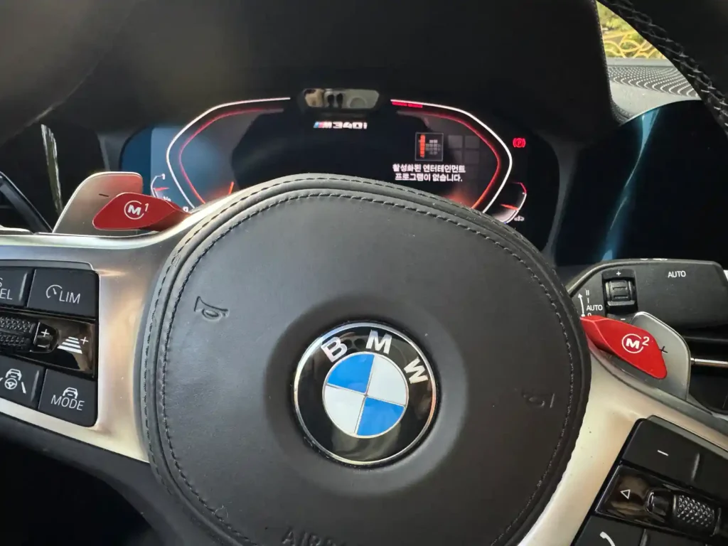BMW M340i steering wheel with red M1 and M2 buttons — driving mode customization by TACO