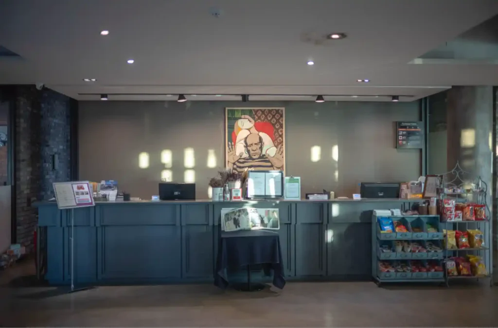 강화 에버리치 호텔 1층 로비, 프런트 데스크와 인상적인 벽 그림, 아침 햇살이 비추는 체크아웃 공간