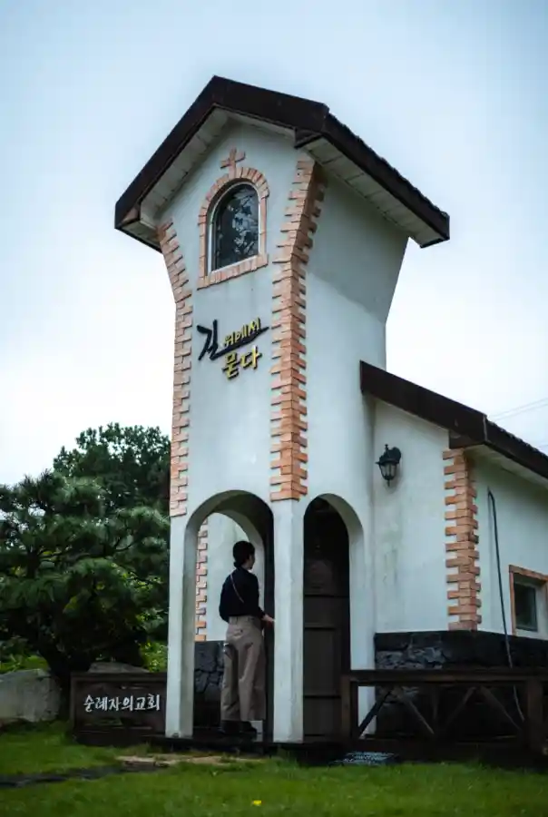 교동도 순례자의 교회 외관, 종탑이 있는 하얀 건물과 '길 위에서 묻다' 문구