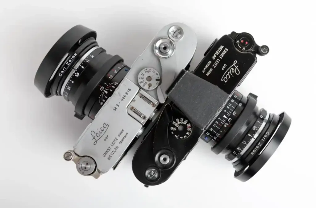 Top view of two Leica M3 rangefinder cameras, silver and black, showcasing their mechanical dials and timeless design.