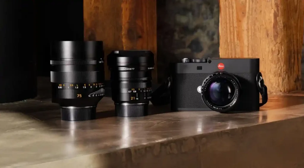 Leica M EV1 camera with Summilux 21mm and 75mm lenses on a wooden surface, symbolizing Leica’s EVF evolution and precision focusing.