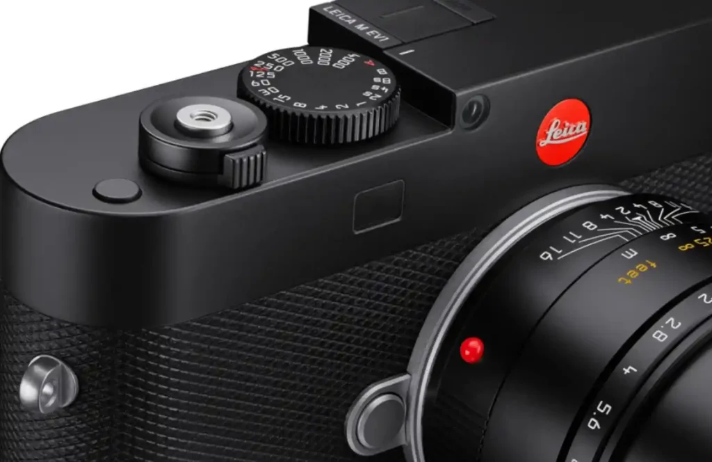 Close-up view of the Leica M EV1’s top plate, showing the shutter dial, EVF housing, and classic Leica red logo, representing the fusion of tradition and innovation.