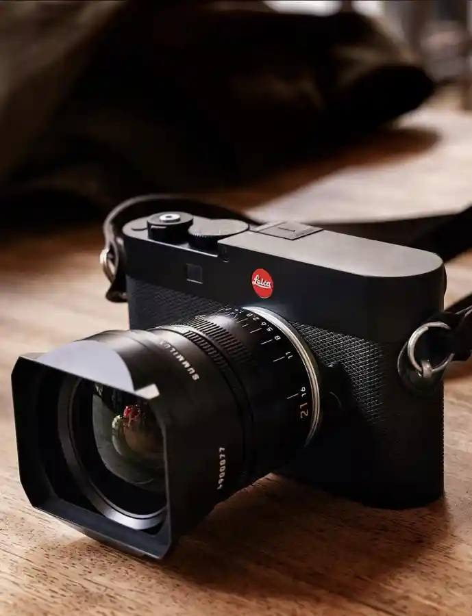 Leica M EV1 camera resting on a wooden surface, highlighting its refined top design and modernized form inspired by the M11 series.