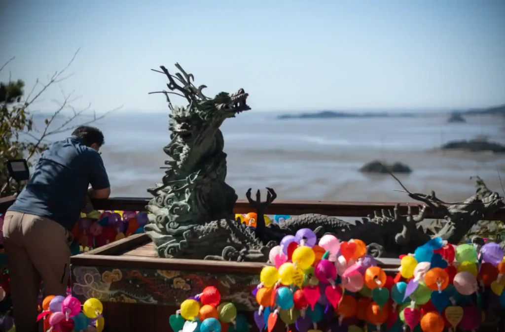 석모도 보문사 용왕당 앞, 청록색 용 조각상과 연등, 그 너머로 펼쳐진 서해 갯벌 풍경 스냅