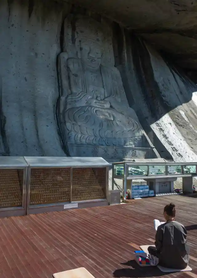 석모도 보문사 마애관음보살좌상 정면 전경, 높이 9.2m 거대 불상과 데크에 앉아 기도하는 사람의 모습