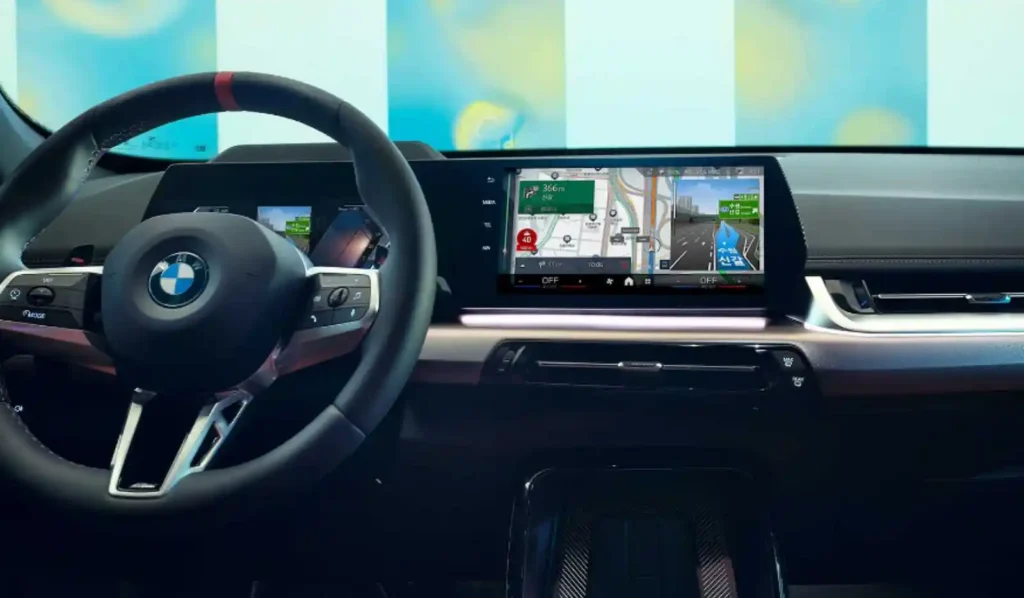 첨단 와이드 디스플레이와 내비게이션 화면이 보이는 자동차 운전석 내부. 차량 내 첨단 안전 장치와 운전 습관 앱 활용을 상징함.