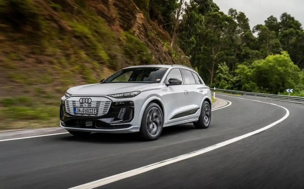 은색 아우디 Q6 e-tron이 산길의 곡선 도로를 달리는 모습, 800V 플랫폼 기반 전기 SUV의 역동적인 주행 장면