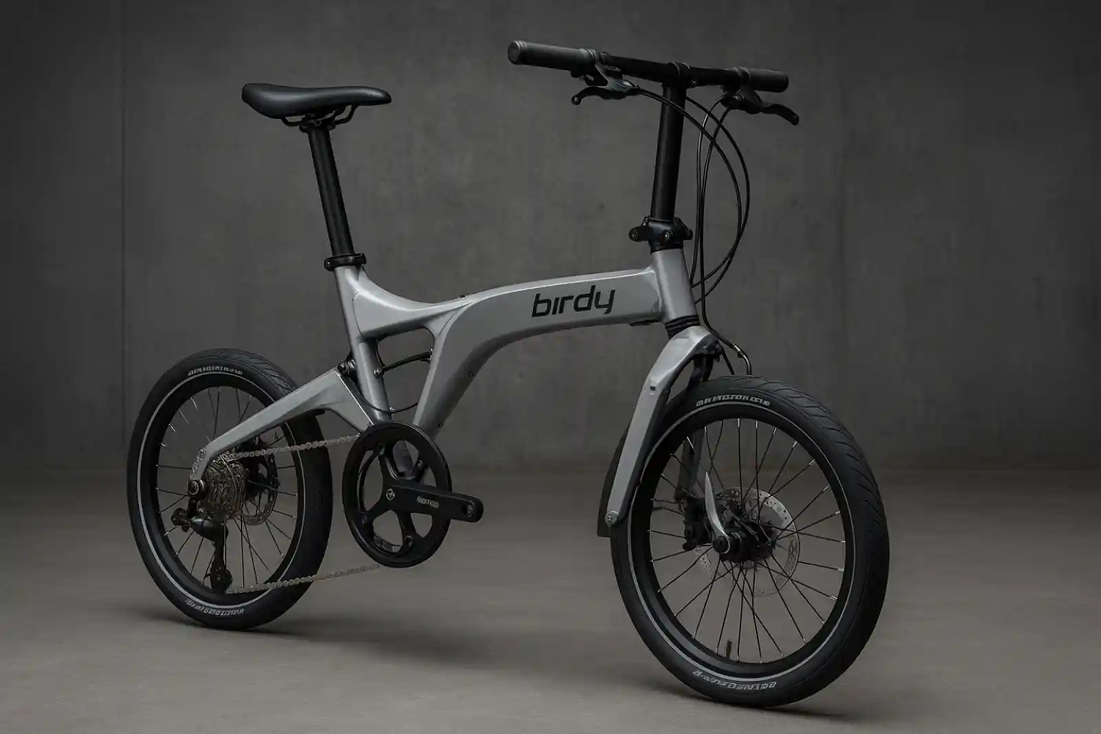 Birdy 폴딩바이크의 알루미늄 모노코크 프레임과 전후 서스펜션이 강조된 정면 사선 이미지. 산업적 콘크리트 배경 속에서 독일식 정밀함과 미니멀한 디자인이 돋보인다.
