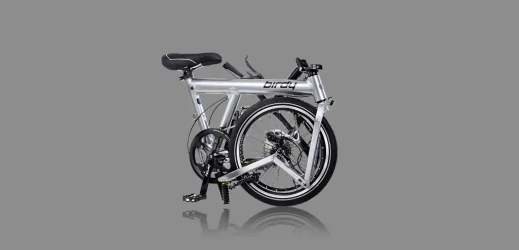 접은 상태의 Birdy Classic 폴딩바이크 전측면 이미지. 알루미늄 프레임과 컴팩트한 폴딩 구조가 강조되어 있으며, 회색 배경 위에 정제된 실루엣으로 배치되어 있다.