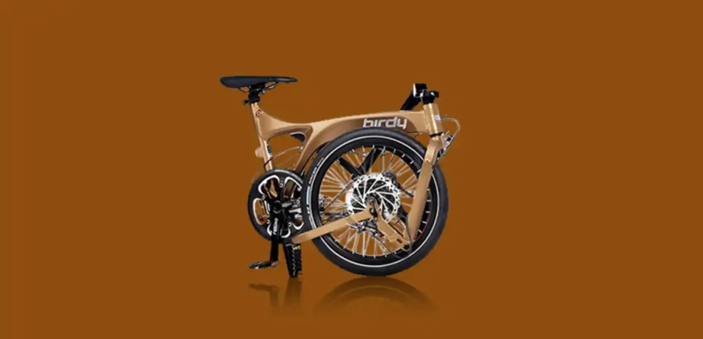 접은 상태의 Birdy Touring 폴딩바이크 전측면 이미지. 브론즈 톤 알루미늄 프레임과 디스크 브레이크가 강조되어 있으며, 장거리 주행용 모델 특유의 견고함이 느껴진다.