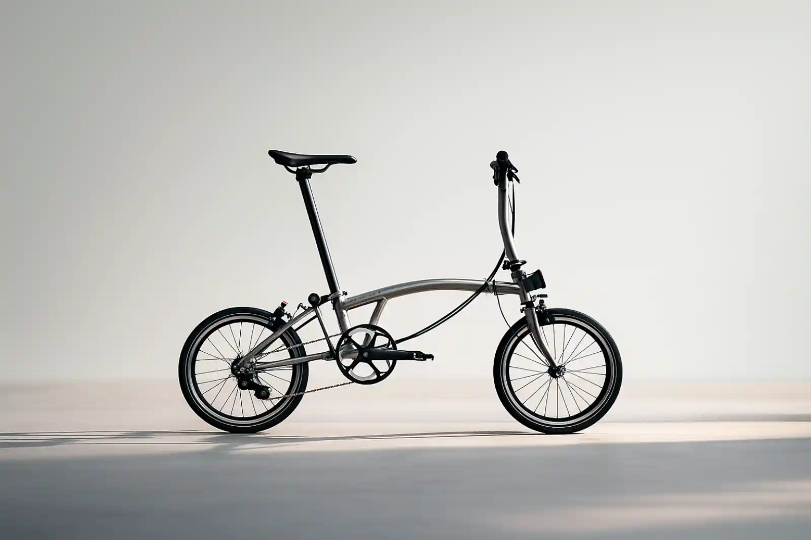 브롬톤 T Line 스타일의 초경량 폴딩자전거가 미니멀한 스튜디오 배경에서 사이드뷰로 놓여 있는 모습