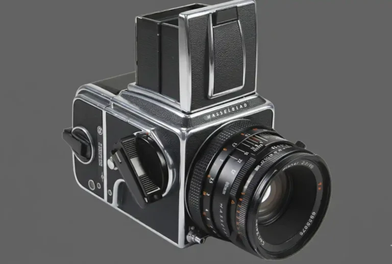 Hasselblad V 시스템 필름 카메라가 차콜 배경 위에 놓여 있는 모습. 금속 바디와 칼 자이스 렌즈가 선명하게 보이는 중형 포맷 카메라 클로즈업
