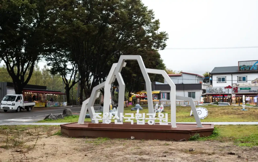 주왕산국립공원 입구 조형물과 이른 아침의 주차장 풍경, 상점들이 하나둘 문을 여는 모습