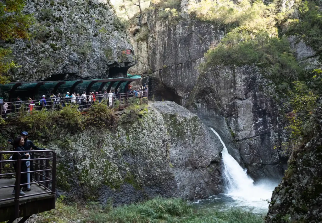 거대한 바위 협곡 사이 용추폭포와 관람 데크에 모인 등산객들