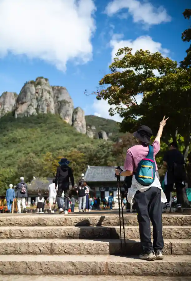 맑게 갠 하늘 아래 주왕산 기암과 대전사 앞에서 브이를 하는 등산객