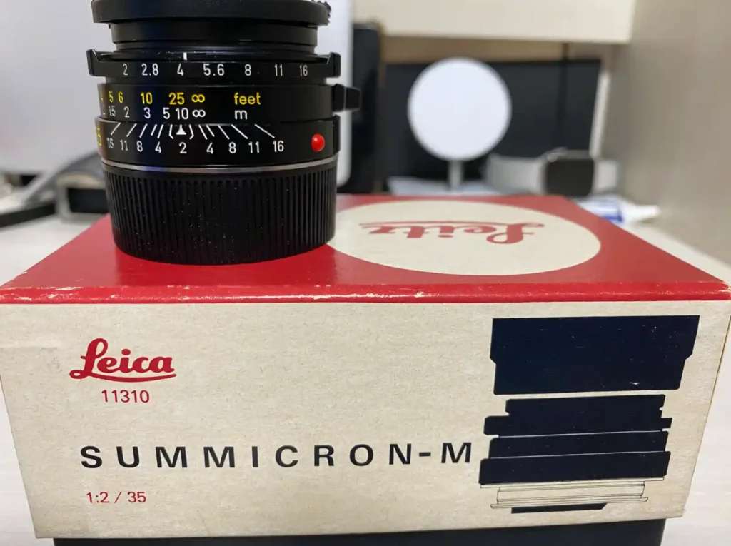 라이카 Summicron-M 35mm f/2.0 4세대 렌즈가 빈티지 라이카 박스(11310) 위에 놓여있는 모습. 조리개와 초점거리 눈금이 선명하게 보임