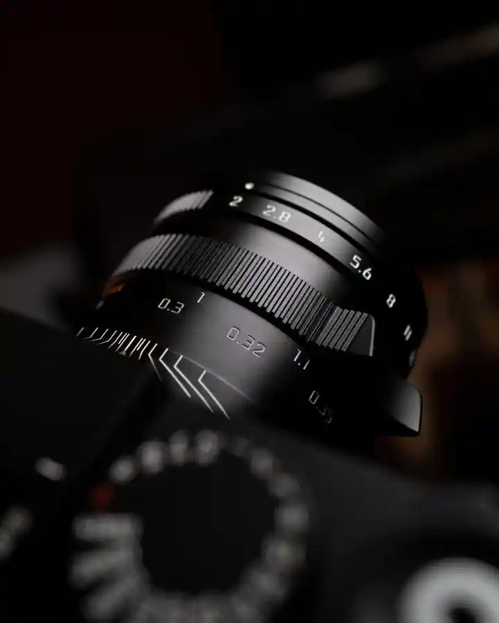 라이카 M 렌즈의 정밀한 조리개 링과 초점거리 눈금이 선명하게 보이는 근접 촬영. 다크한 배경에서 렌즈의 프리미엄 질감이 돋보임