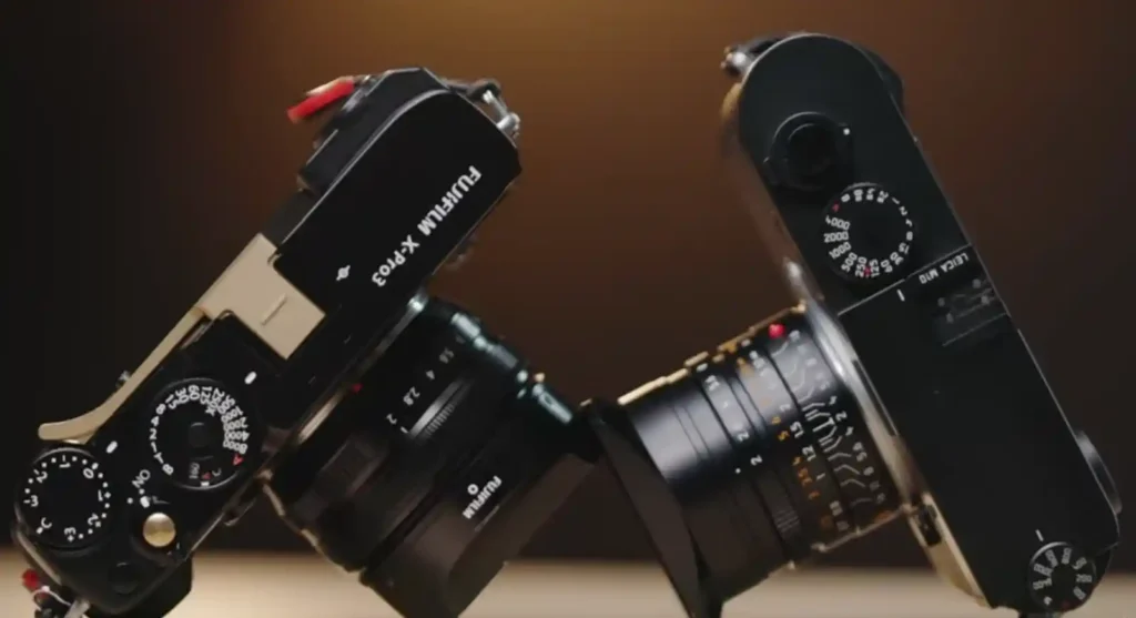 후지필름 X-Pro3와 라이카 M10 카메라가 서로 마주 보고 있는 장면. 두 브랜드는 각각 하이브리드 뷰파인더의 실험과 클래식한 레인지파인더 철학을 상징하며, 하이브리드 M의 가능성을 시각적으로 보여줍니다.