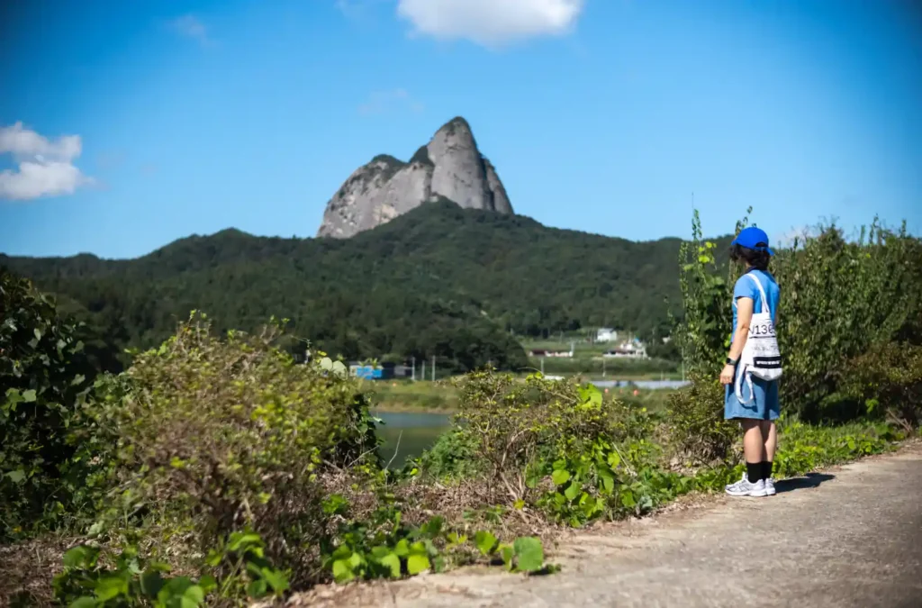 진안 마이산을 배경으로 파란 하늘 아래 서 있는 한 사람의 뒷모습. 초록빛 산과 하늘의 대비가 선명하게 드러난 M10-R 촬영 사진.