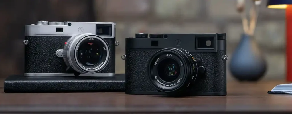 실버와 블랙 두 가지 색상의 Leica M11-P가 테이블 위에 놓여 있습니다. Summilux와 Summicron 렌즈가 장착된 모습으로, M11-P 특유의 미니멀한 외관과 레드닷 없는 디자인이 선명하게 보입니다.