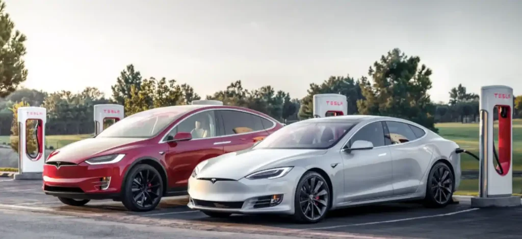 테슬라 모델 S와 모델 X가 슈퍼차저 충전소에서 충전 중인 모습. 야외 충전소에서 두 차량이 나란히 서 있는 장면