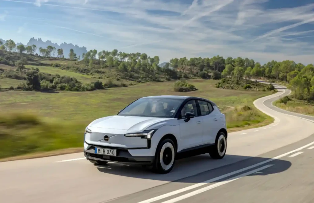 볼보 EX30 전기 SUV가 유럽 시골 도로를 주행하는 모습, 흰색 차체와 자연 배경